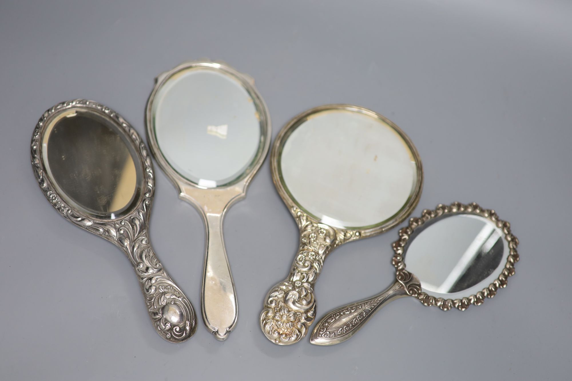 Four assorted hand mirrors including two silver and two white metal, largest 31cm.